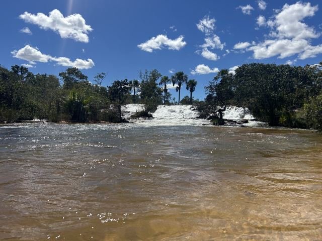 Areia clara, água morna e corredeiras ao fundo